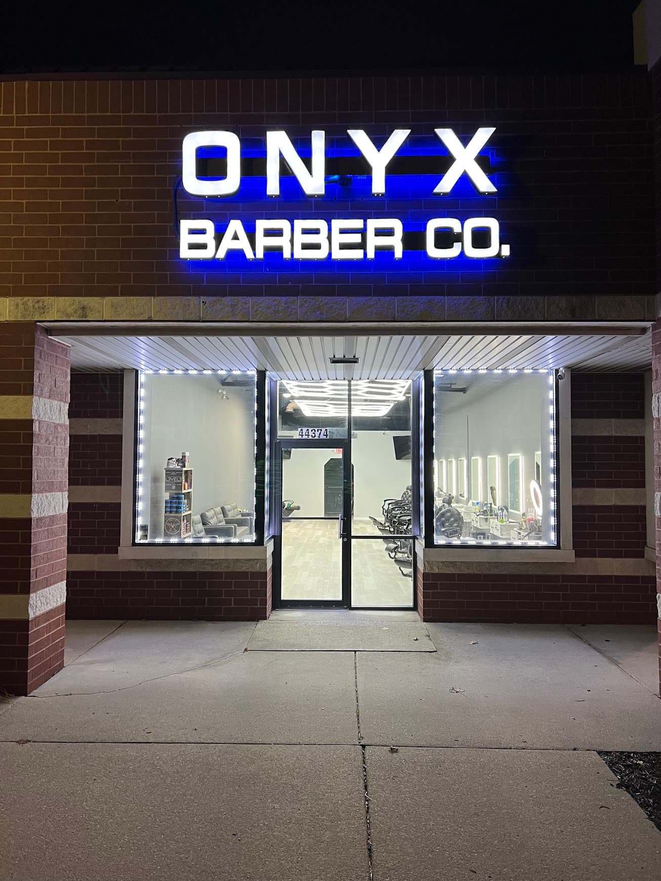 The Onyx Barber Co. storefront lit up at night in Canton, Michigan